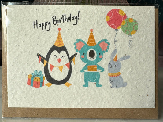 a happy birthday card featuring a penguin, a koala and a bunny each holding various party items