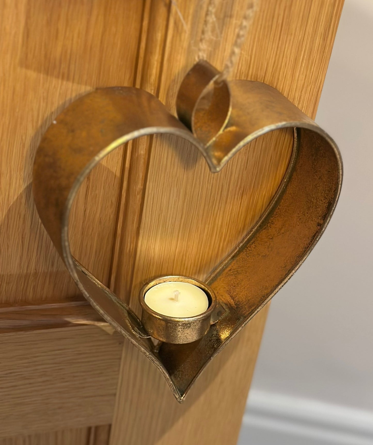 Metal heart-shaped hanging tealight candle holder in antique gold finish, perfect for warm romantic home lighting