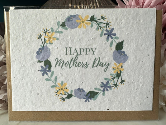 a yellow and blue wreath with the words 'happy mothers day' printed inside of it, on wildflower seed paper