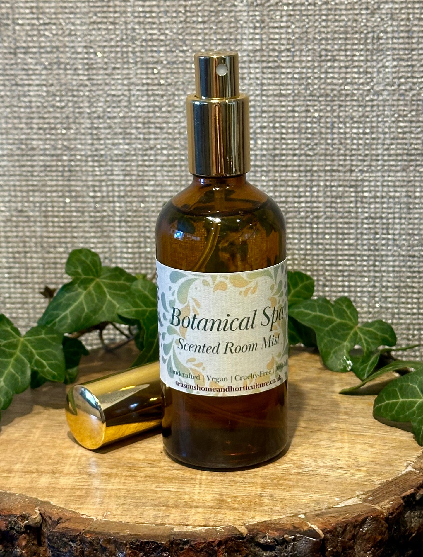 Botanical spa room mist in an amber spray bottle with lemongrass, patchouli, and ginger notes, creating a fresh, relaxing home fragrance ambiance