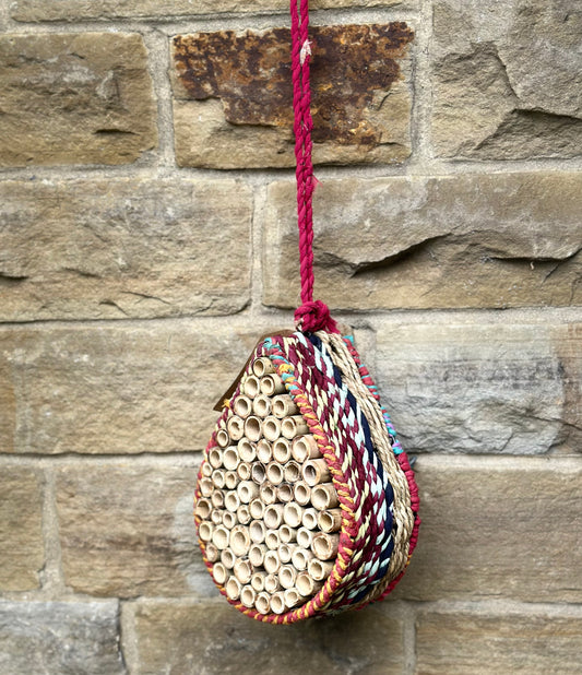 Eco-friendly hanging bug hotel made from munja grass and reclaimed sari fabric for garden pollinators