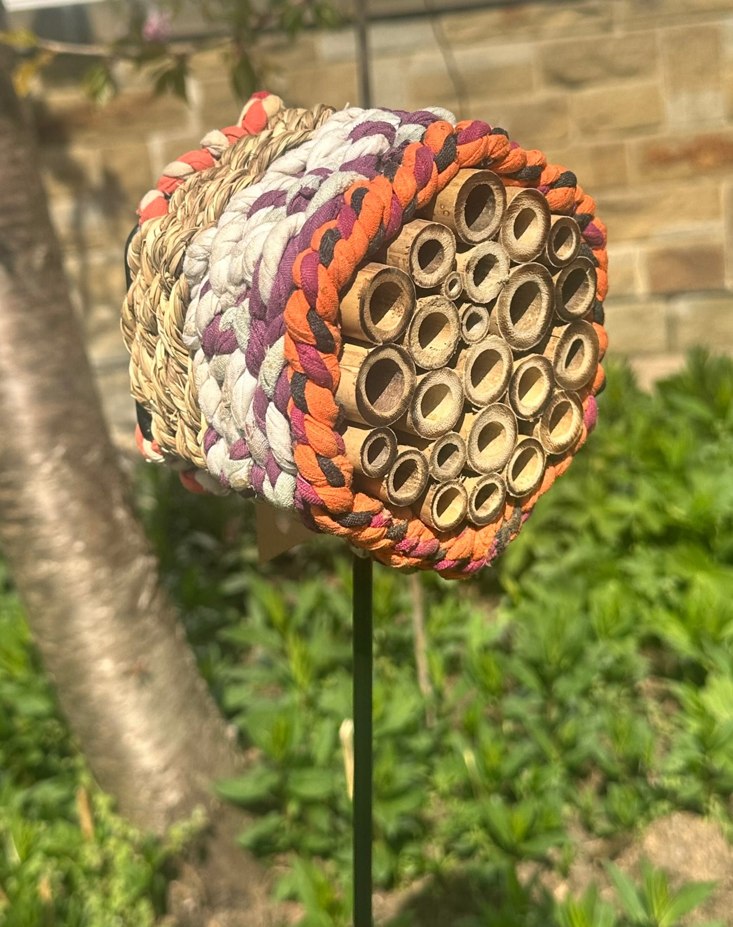 Close-up of handcrafted Munja grass bee hotel for solitary pollinators in a natural garden setting
