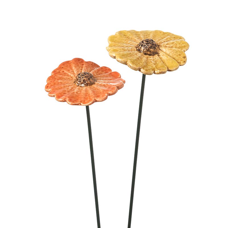yellow and orange ceramic daisy stakes against a black background