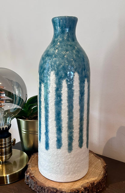 Decorative vase with blue and white pattern on a wooden stand against a plain background
