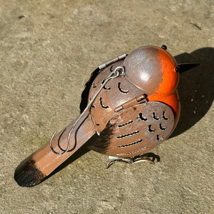 Decorative bird ornament with orange head and brown body on a concrete surface