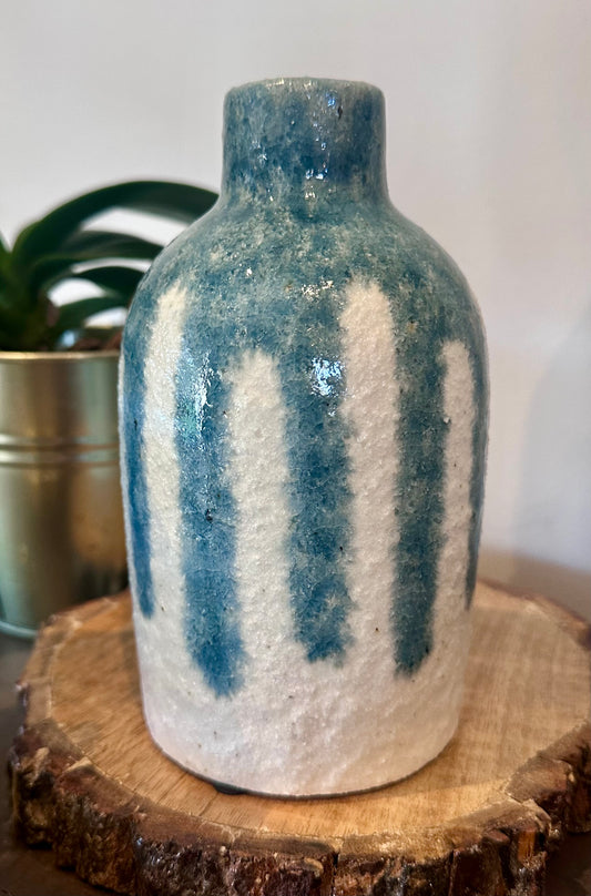 Decorative ceramic vase with blue and white stripes on a wooden surface