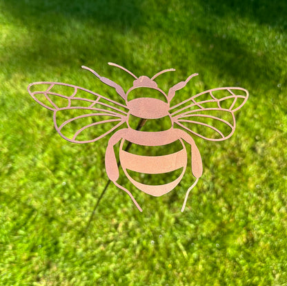 Metal bee-shaped garden stake on grass