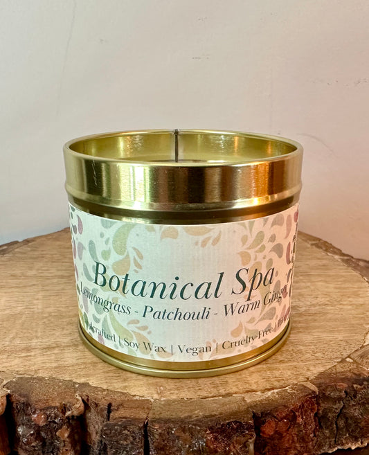 Botanical Spa soy candle with lemongrass, patchouli and warm ginger scent in gold tin on wooden surface