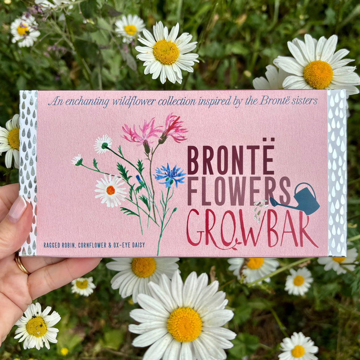 Bronte Flowers Growbar product packaging held in front of wildflowers