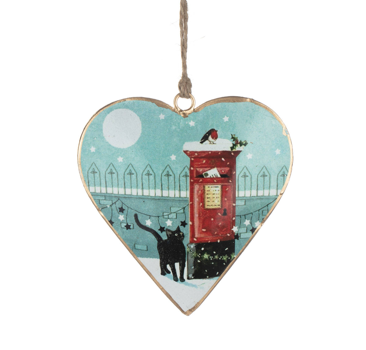 A heart-shaped hanging ornament with a gold-toned edge, featuring an illustrated winter scene with a red post box, a black cat, snow, and a pale blue sky. The ornament hangs from a twisted jute string against a plain white background.