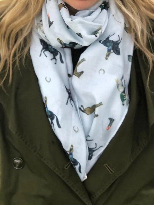 Person wearing a light blue scarf with horse prints over a green coat.
