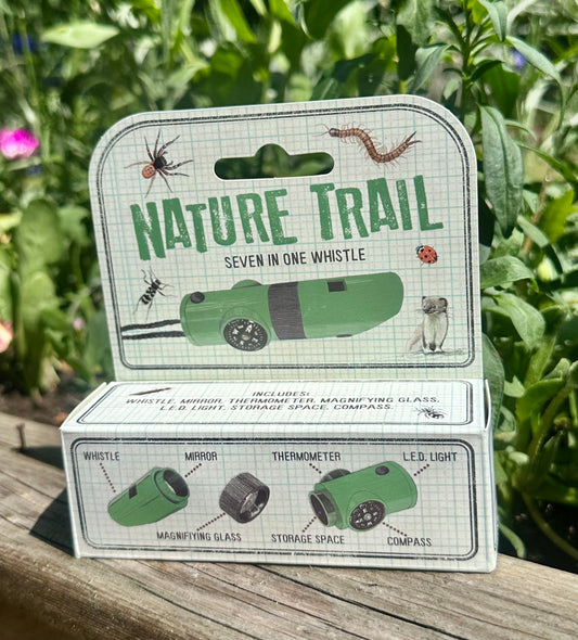 Nature Trail product whistle torch thermometer packaging with green and white design on a wooden surface with plants in the background