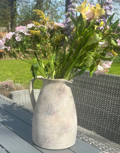 a large stoneware vase/jug with flowers in