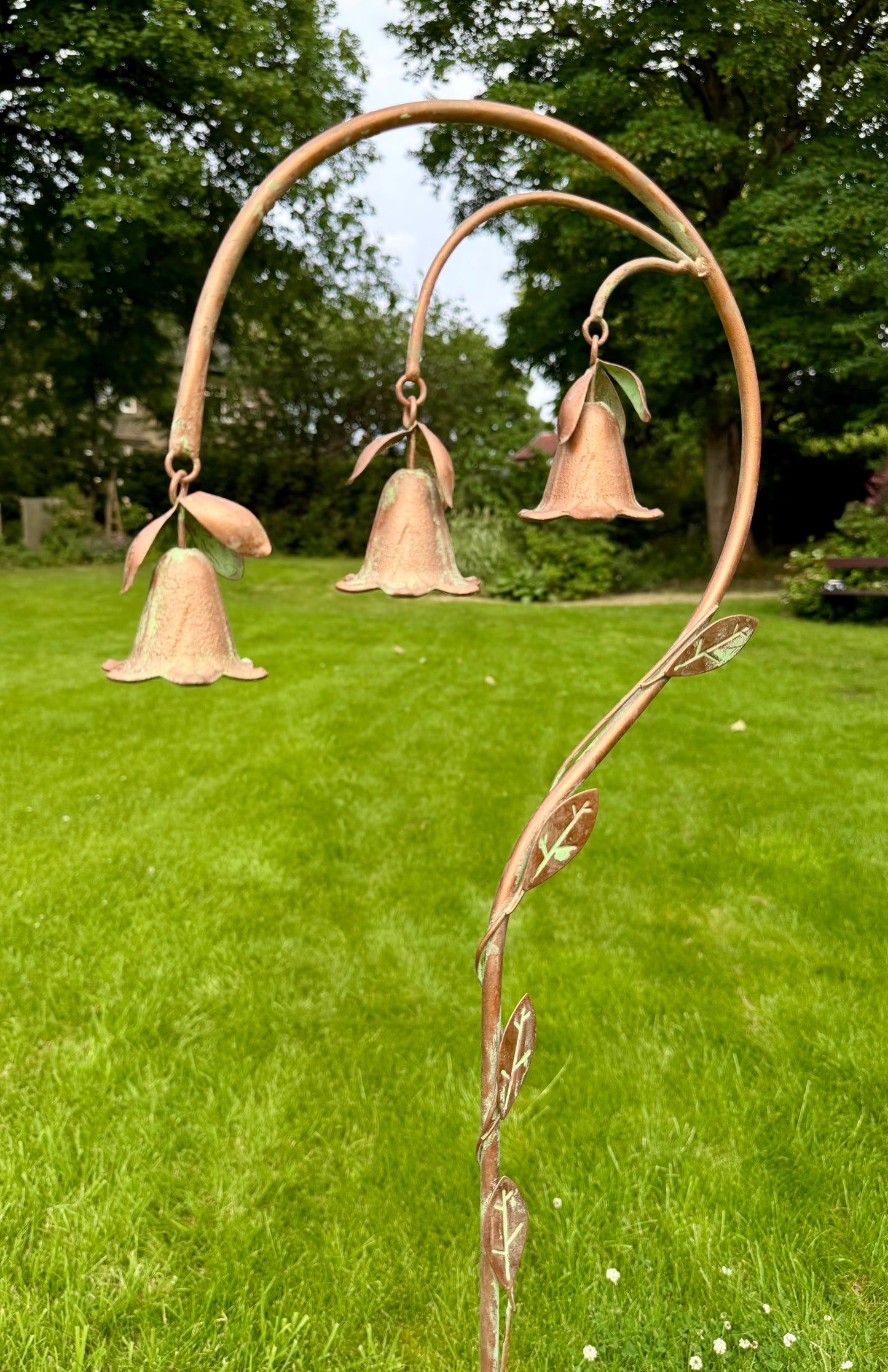 Metal garden stake with hanging bell flowers displayed outdoors as decorative garden ornament