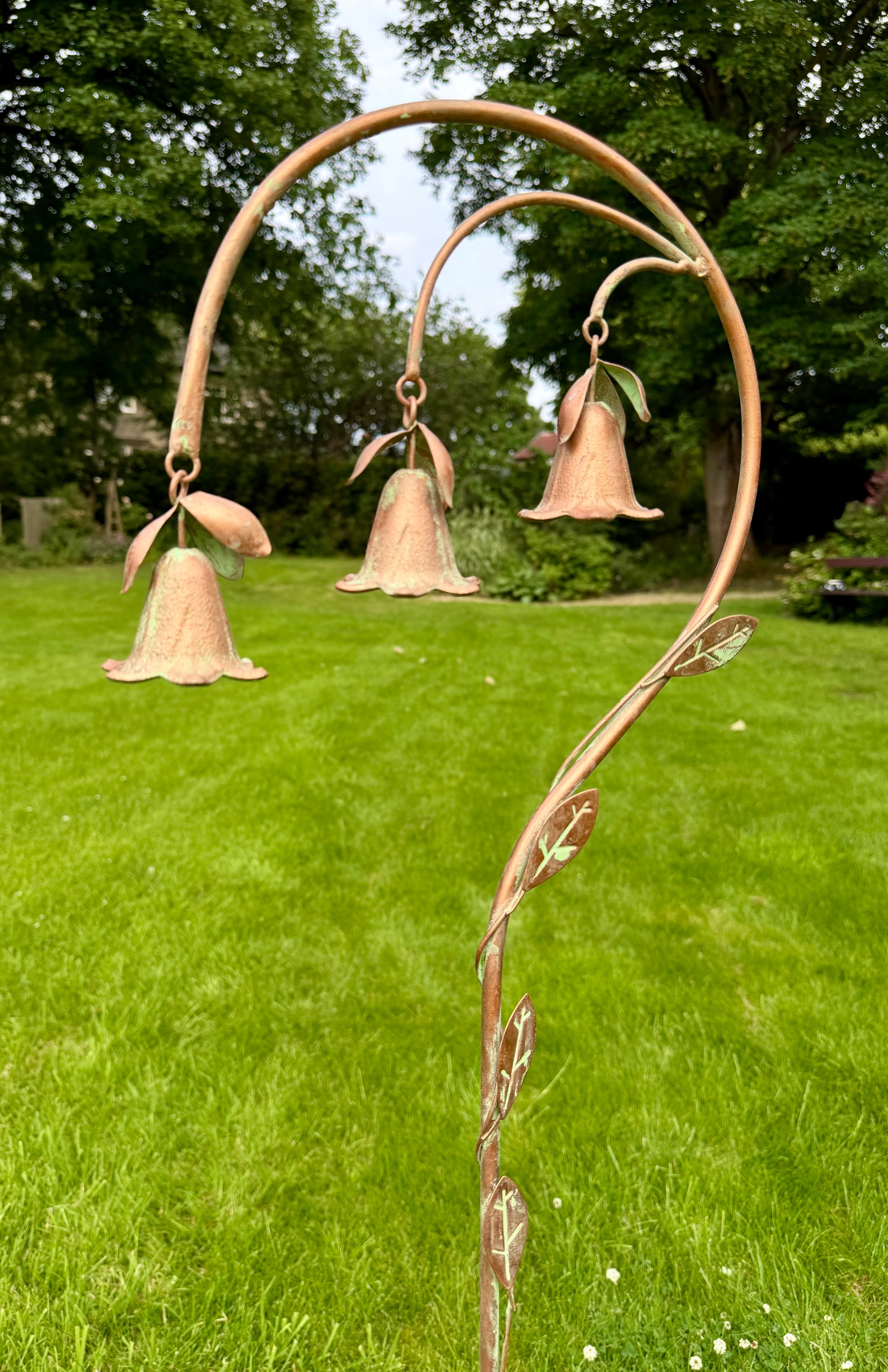Metal garden stake with hanging bell flowers displayed outdoors as decorative garden ornament