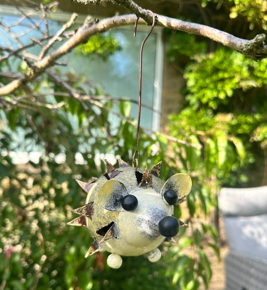 Decorative tealight holder shaped like a hedgehog hanging from a tree branch.