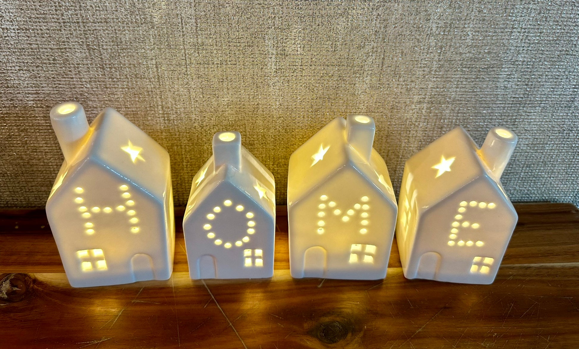 Illuminated ceramic house led lights forming the word HOME — elegant glowing lanterns for winter interiors, festive décor, and stylish home gifts.