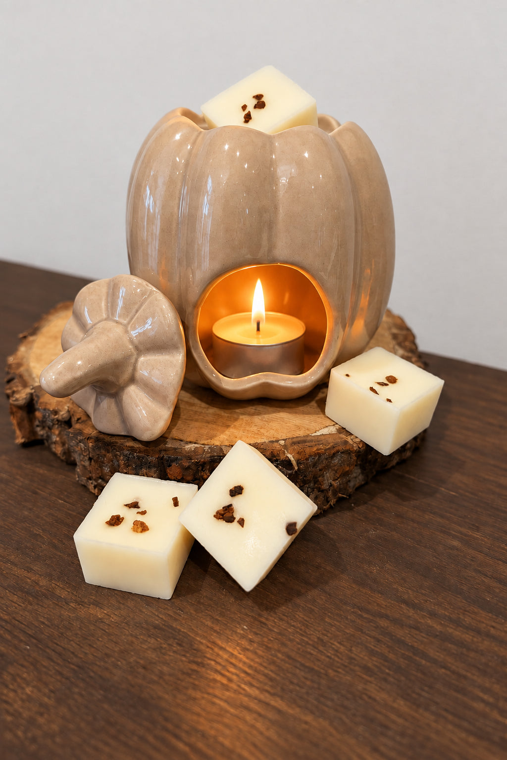 wax melt burner in a ceramic pumpkin with wax melts against wood surface