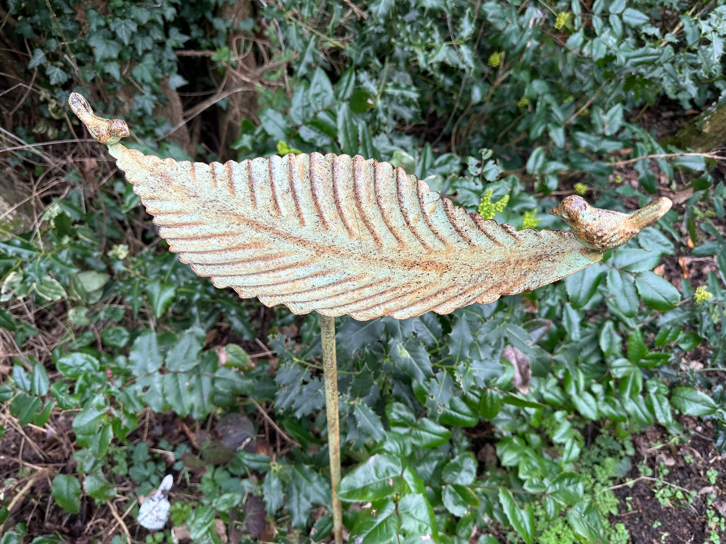 Decorative leaf sculpture in front of green foliage
