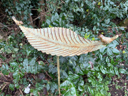 Decorative leaf sculpture in front of green foliage