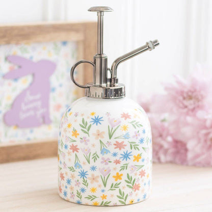 Floral-patterned spray bottle plant mister on a light surface with a blurred background