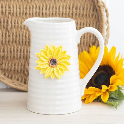 Cream ceramic pitcher with 3D sunflower design on a wooden surface