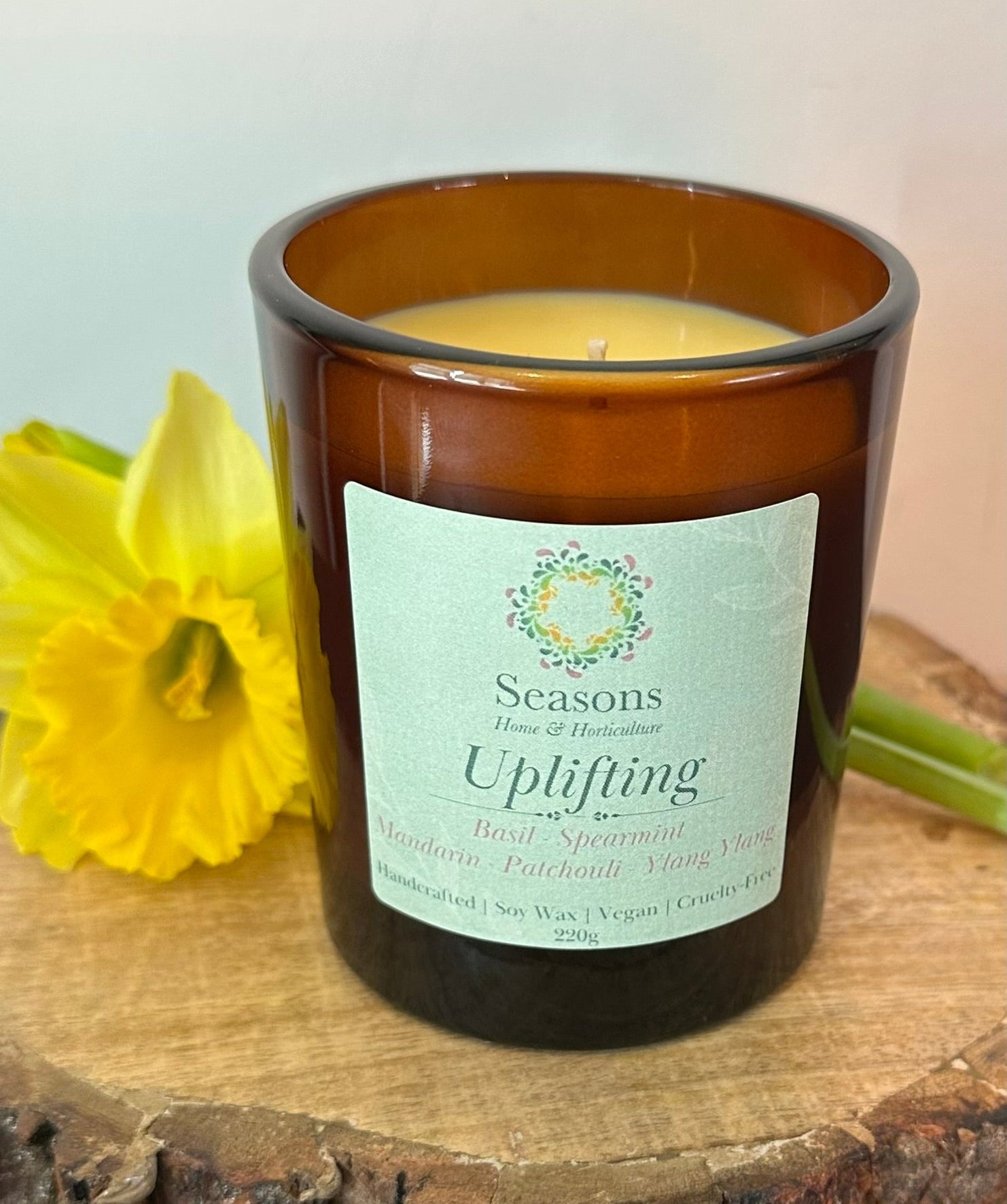Uplifting soy candle with basil, spearmint, mandarin, patchouli and ylang ylang in amber glass jar with yellow flower